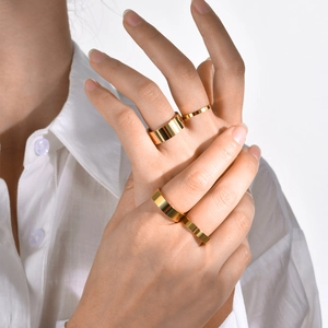 Close-up of set of four minimalist gold stainless steel rings on a model finger