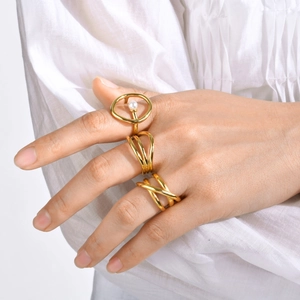 Tres anillos minimalistas dorados con perla y diseños de ondas en la mano de modelo