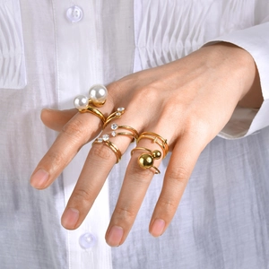 Detalle de anillos dorados apilables con perlas blancas y circonitas en la mano del modelo