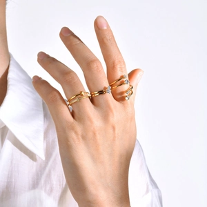 Detalle de anillos apilados de acero dorado con cruz y piedras brillantes