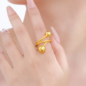 Vista de detalle de un anillo espiral dorado con esferas metálicas en el dedo