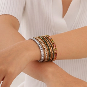 Gros plan de bracelets multicouches en acier doré 18K sertis de zircons colorés