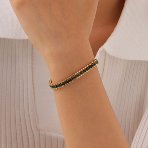 Détail d'un bracelet double corde plaqué or 18 carats avec zircons verts sur poignet