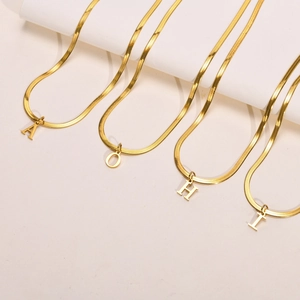 Detalle de collares de cadena de serpiente en acero chapado en oro con letras A O H I
