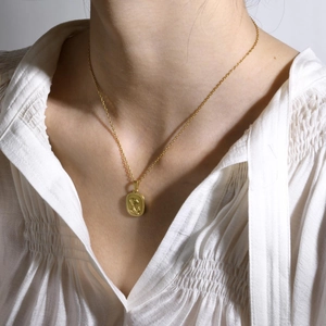 Elegante collana con ciondolo a rosa in rilievo in acciaio inossidabile dorato su modella