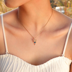 Primer plano del collar con lazo dorado y colgante de corazón de circón azul en modelo