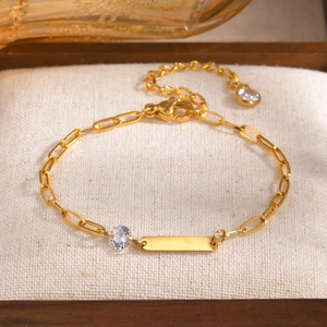 Vue détaillée du bracelet gourmette doré avec plaque à graver et pierres en zircone brillant