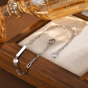 Gros plan d'un bracelet barre en acier inoxydable argenté avec zircon sur coussin en lin
