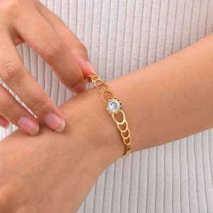 Detail of a gold-plated stainless steel cuff featuring Roman numerals and a central crystal