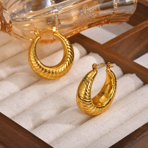Detail view of gold textured C-shape earrings displayed in a velvet jewelry box