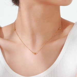 Élégant collier chaîne en acier inoxydable doré avec trois perles sur un mannequin