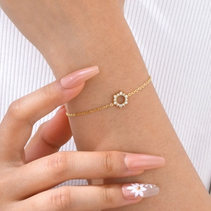 Detail of a golden sunflower bracelet with white zircons worn on a female wrist