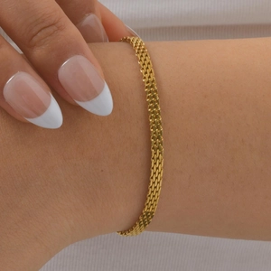 Macro shot of gold mesh strap bracelet on wrist showcasing detailed Milanese weave texture