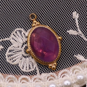 Detailansicht eines facettierten lila Steins in einer vergoldeten Fassung im Vintage-Stil