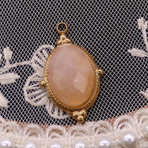 Detail eines facettierten ovalen Edelsteinanhängers mit goldenem Perlenrahmen