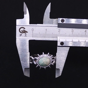 Measuring silver titanium steel ring with oval turquoise stone using a caliper tool