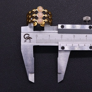 Macro view of measuring the triple-layer gold ring width using a metal caliper tool