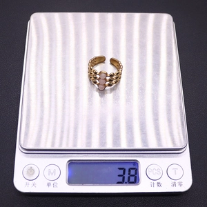 Detailed shot of an adjustable gold ring with pink stones on a scale weighing 3.8g