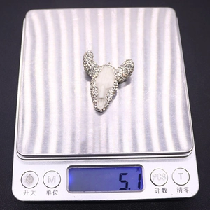 Detailweergave van een hars stierenschedel hanger met strass op een digitale weegschaal 5,1g