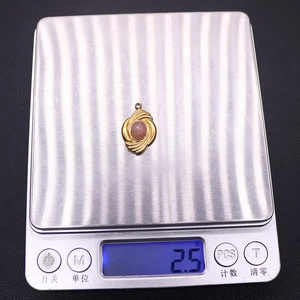 Macro detail of 2.5g gold-plated pendant with natural stone on a digital scale