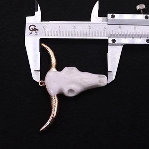 Macro view of acrylic bull skull pendant with gold horns and bone texture on black felt