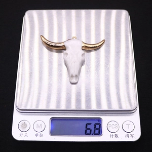Macro view of bull skull acrylic pendant weighing 6.8 grams on a precision digital scale