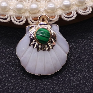 Macro detail of fan-shaped shell pendant with turquoise inlay and gold plated metal edges