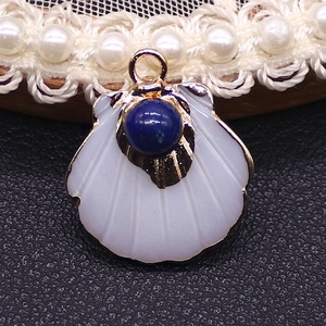 Detailed view of scallop shell pendant with blue gemstone inlay and gold metal base