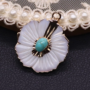 Macro detail of white peach blossom shell pendant with turquoise stone and golden edge