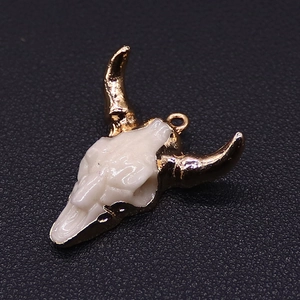 Macro shot of bohemian bull skull pendant with white resin and gold metallic horns