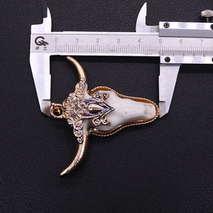 Detail van stierenschedel hanger met gouden snijwerk en breedtemeting van 5,2 cm breed