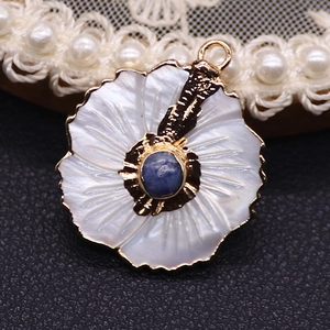 Macro detail of peach blossom shell pendant with blue gem and golden petals