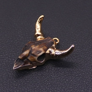 Macro detail of acrylic bull head pendant with golden horns and vintage bone texture