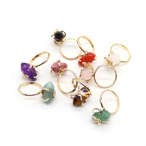 Adjustable gold rings with hexagonal natural stones and a small bee accent on white background