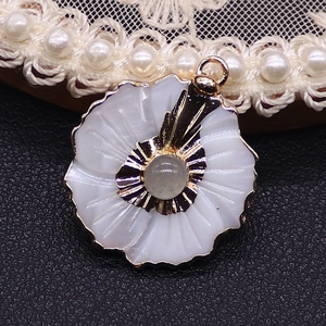 Detail view of flower shell pendant with grey crystal center and gold plated metal