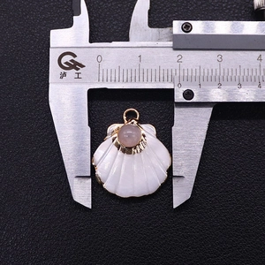 Macro shot showing width measurement of a shell pendant with pink stone and gold plating