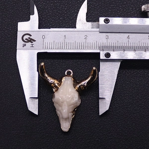 Macro detail of bull skull pendant with gold horn finish measuring 2.8cm wide