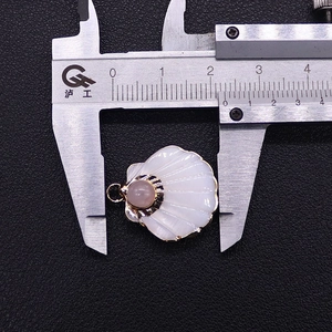 Detailed close-up of shell pendant with pink stone inlay showing 25mm width on caliper