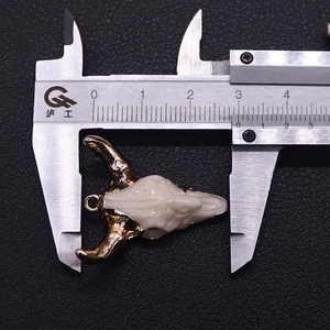 Macro view of bull head pendant with gold plated horns measured by a caliper tool