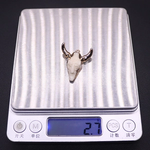 Macro view of a resin bull head pendant weighing 2.7g on a digital scale for DIY jewelry