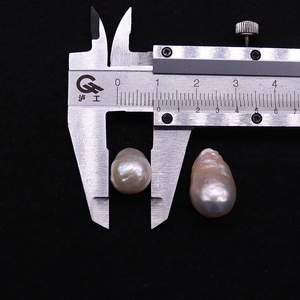 Macro view measuring two baroque Edison pearls with a caliper on black velvet background