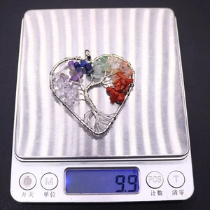 Macro shot of a wire wrapped tree of life heart pendant on a scale weighing 9.9 grams