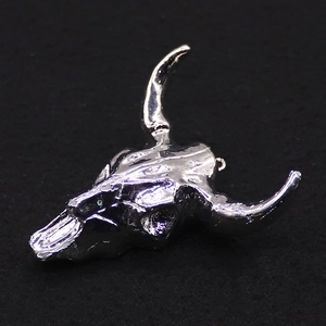 Gros plan du pendentif crâne de taureau argenté avec finition miroir et texture d'os