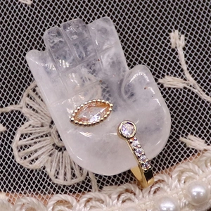 Detailed close-up of golden open ring with marquise and round cut gems on hand display
