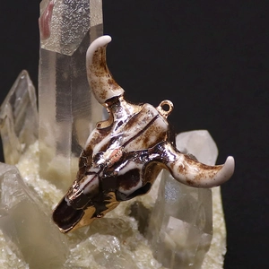Makro-Detail von Acryl-Stierkopf-Anhänger mit Goldrand auf weißem Kristallhaufen