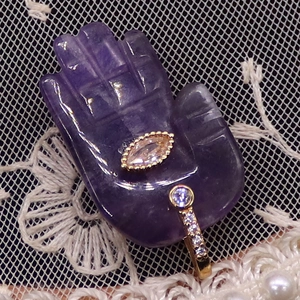 Macro view of purple amethyst Hamsa Hand pendant with gold micro-pave cubic zirconia ring
