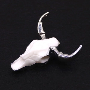 Détail du pendentif crâne de taureau en résine avec cornes argentées et texture d'os