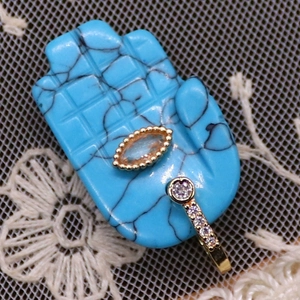 Macro view of blue Hamsa hand pendant with gold accents and sparkling crystal stones