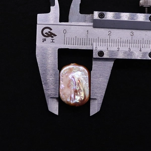 Macro shot measuring a 13.5mm irregular pink baroque freshwater pearl with a caliper