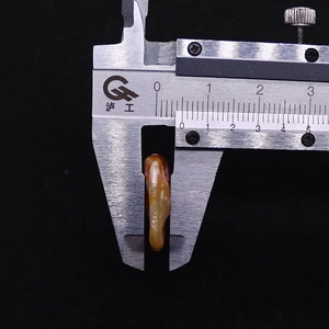 Measuring the 5-6mm thickness of a natural baroque purple pearl using a vernier caliper